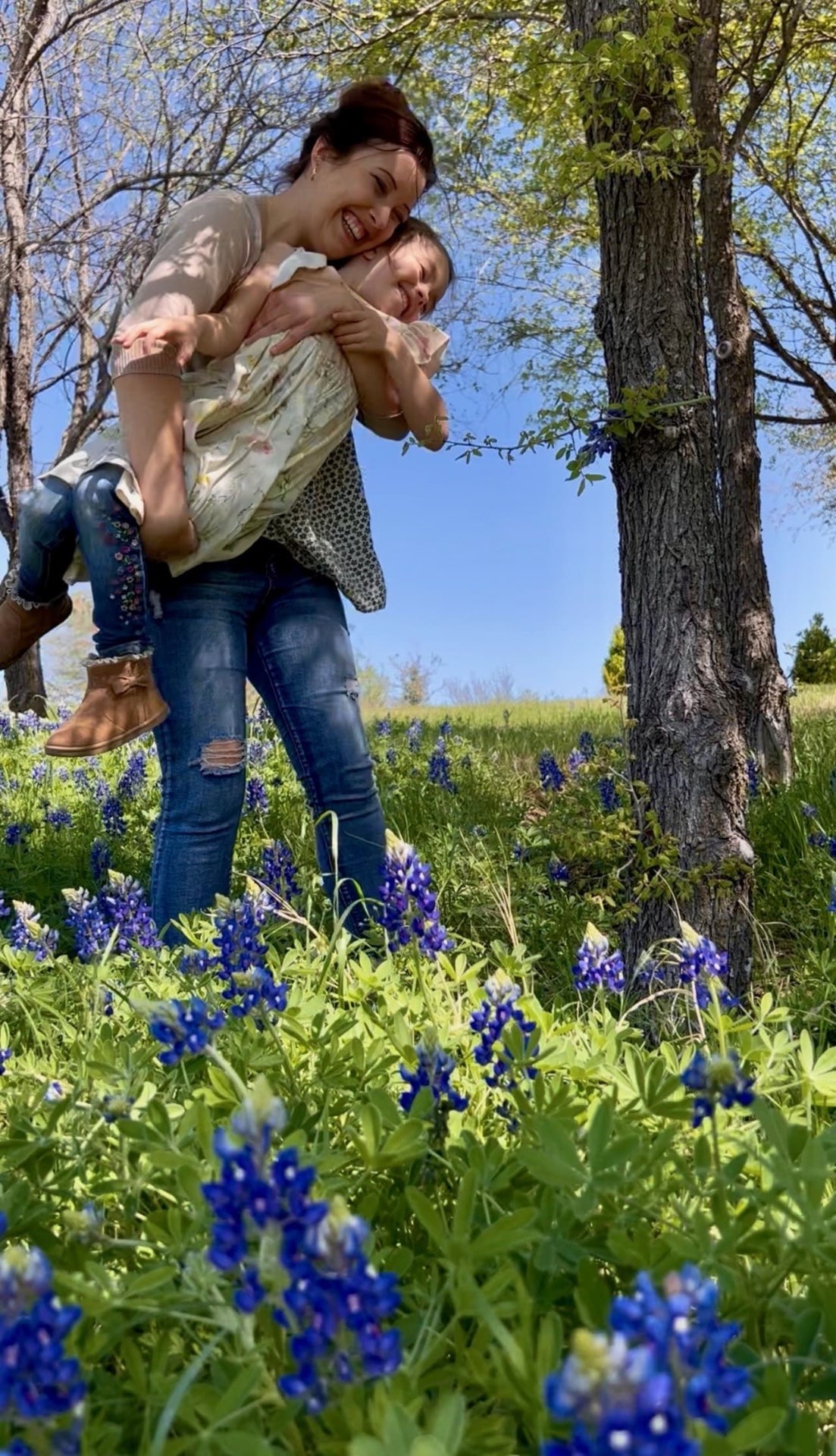 Alyssa giving her daughter a piggyback in a wildflower field