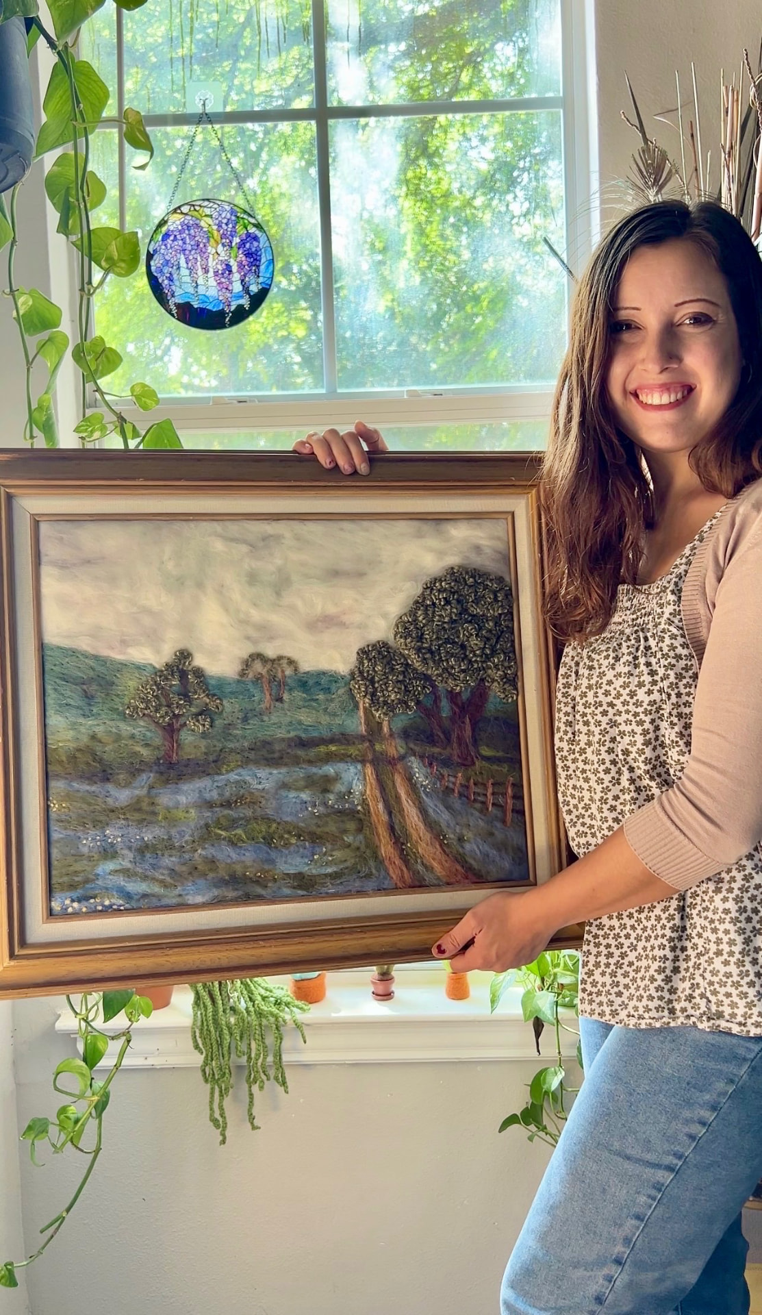 Alyssa holding a large framed needle-felted landscape